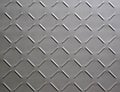 Abstract background of metal plate with diamond pattern painted grey close up.