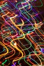 Abstract background of multicolored chaotic glowing neon wavy stripes on dark.