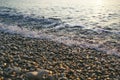 Abstract background of oncoming sea wave surf on pebble beach closeup on sunrise