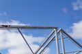 Abstract background of overhead pipes against a blue sky with clouds