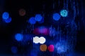 An abstract background of red and blue police lights bokeh trough wet glass at night close-up with selective focus