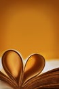 Abstract background with a tan accent. Old book. An open book with a heart folded from folded sheets. Love education concept