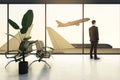 Abstract backlit image of businessman looking out of window to look at airplane in airport. Royalty Free Stock Photo