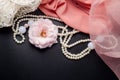 Abstract beauty decoration background with flower, pearl necklace and pink fabric on black table Royalty Free Stock Photo