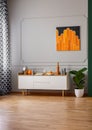 Black and orange painting on empty grey wall of stylish room