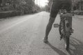 Abstract black and white image of woman sitting on old bicycle and riding on concrete road in the morning.