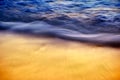 Abstract blue and golden silky ocean waves crashing on shore. Royalty Free Stock Photo