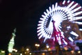 Blurred bokeh night harbor lights background with ferris wheel