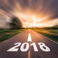 Abstract blur number of 2018 for New Year concept on country road, field and blue sky with white clouds. Royalty Free Stock Photo