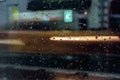 Abstract blurred colorful background. View through glass window with rain drops on bokeh city lights, night street scene Royalty Free Stock Photo