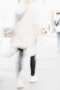 Abstract blurred image of unrecognizable silhouettes of girl walking in city street. Urban modern background.