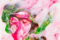 Abstract blurred pink-green texture of food dyes in milk.