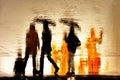 Abstract blurred silhouettes of moving people holding umbrellas
