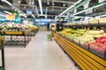 Abstract blurred supermarket aisle with colorful shelves and unrecognizable customers as background. Fruit and vegetable section
