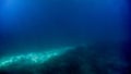 Abstract blurred underwater shot of sea bottom and sun rays shining through water surface. Royalty Free Stock Photo