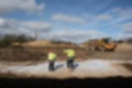 Abstract blurred workers in high vis jackets and hard hats on a construction site with dumper digger truck