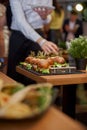 Abstract blurry food background. Small burgers with meat, salads cheese and tomatoes on wooden plate during summer barbecue party Royalty Free Stock Photo