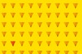 Abstract bright background with one different piece from others whole triangular nachos slices on yellow color