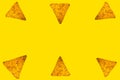 Abstract bright background of whole triangular nachos slices on yellow color with an empty space in the center