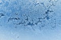 Abstract Christmas background. Ice crystals on frozen window glass. Frost drawing. Winter season patterns. Blue tinted wallpaper. Royalty Free Stock Photo