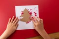 abstract Christmas tree, DIY fingerprint craft, kids hands doing greeting card on red background Royalty Free Stock Photo