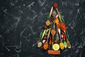 Abstract Christmas tree made from spices in spoons on a black stone background. Top view, flat lay, copy space Royalty Free Stock Photo