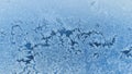 Abstract Christmas wallpaper. Ice crystals on frozen window glass pane. Frost drawing. Winter season pattern. Blue tinted Royalty Free Stock Photo