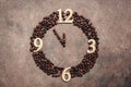 Abstract clock made of roasted coffee beans on a dark brown rustic background. New Year concept. Five minutes to twelve