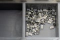 Grey scattered microscopic SMT surface mount chip resistors sorted in grey storage container