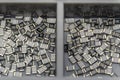 Grey scattered microscopic SMT surface mount chip resistors sorted in grey storage container