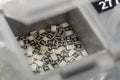 Grey scattered microscopic SMT surface mount chip resistors sorted in grey storage container