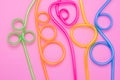 Abstract colorful background of curved cocktail straws. Plastic spiral multicolor tubes on pink paper frame. Fun mood. Minimal des Royalty Free Stock Photo
