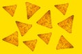 Abstract bright background of whole randomly located triangular nachos slices on yellow color