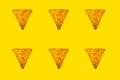 Abstract bright background of whole triangular nachos slices on yellow color