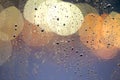 Abstract colorful bokeh background with yellow circles and water drops on glass surface in front. Blurred city lights Royalty Free Stock Photo