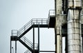 Abstract colourless picture of an iron staircase next to an aluminium pipe at the tower of an industrial plant