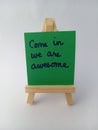 Abstract come in we are awesome sign on a wood easel on a white background