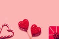 Abstract composition with two decorative hearts, lollipops and red present box on pink paper background Royalty Free Stock Photo