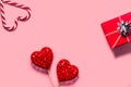 Abstract composition with two decorative hearts, lollipops and red present box on pink paper background Royalty Free Stock Photo