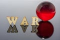 Abstract composition of war. Isolated wooden letters and red glass ball Royalty Free Stock Photo