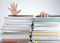 Abstract concept image showing a young student behind a large pile of test prep books on a study desk