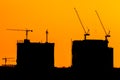 Abstract construction cranes and building silhouettes over sun at sunrise Royalty Free Stock Photo