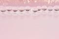 Abstract cosmetic festive background -  glass nucleuses with gold glitter on pastel pink backdrop, copy space. Royalty Free Stock Photo