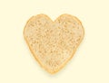 Abstract creative heart shaped cut-out from slice of white bread on light yellow background. Minimal flat lay Royalty Free Stock Photo