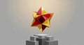 Abstract 3D rendering of a red and yellow geometric star shape composed of overlapping triangles on a gray cube against a light Royalty Free Stock Photo