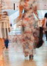 Abstract defocused motion blurred young people walking in the shopping center. Beautiful figure of a girl close-up Royalty Free Stock Photo