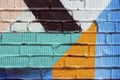 Abstract detail of brick wall with fragment of colorful graffiti. Urban Art close-up, for background use. Royalty Free Stock Photo