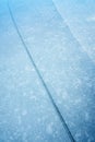 An abstract detailed vertical close up photograph of a crack or fault line in the blue frozen ice layer on a lake