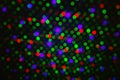Abstract dot defocus background backdrop, rainbow colored green red violet round glitter on black background. Illumination blurry Royalty Free Stock Photo