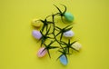 Abstract Easter composition of multicolored eggs, tomato branches and yellow background. Easter background. The concept of spring